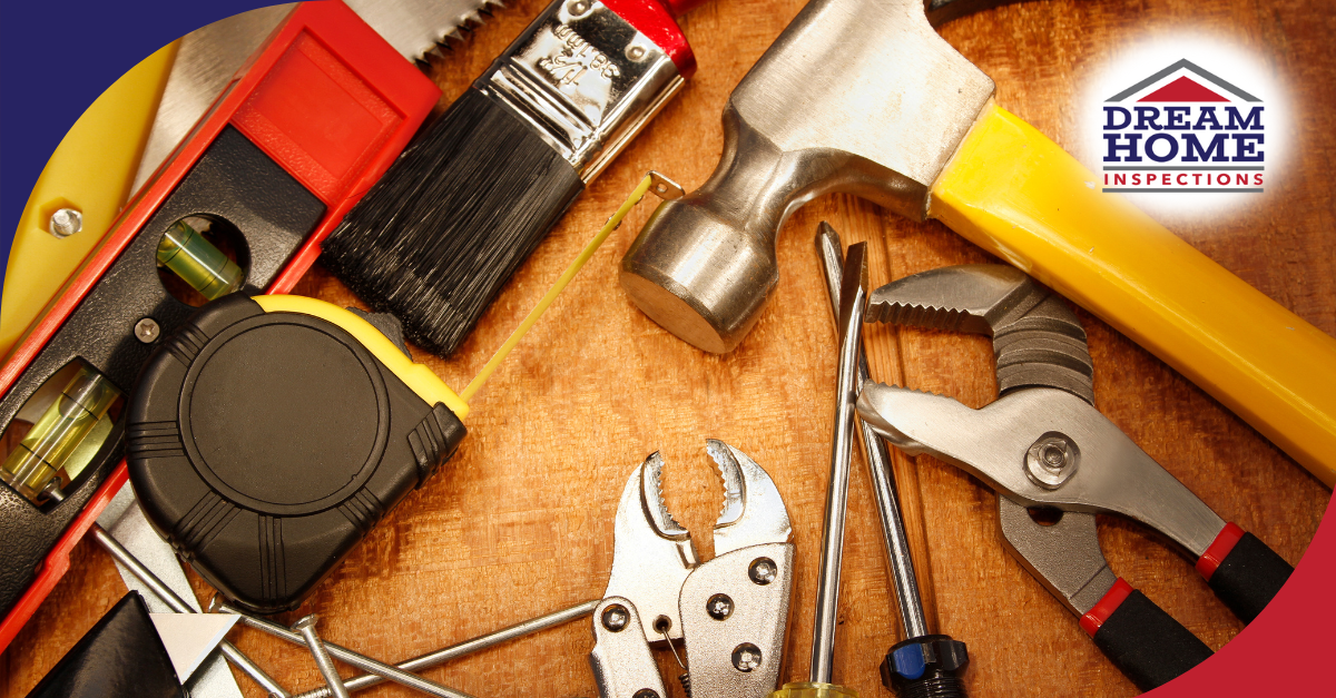Assorted home inspection tools including a hammer, tape measure, and level on a wooden surface.