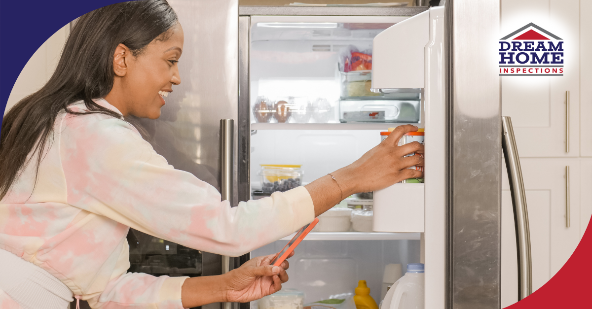 Smiling woman placing food into a refrigerator in a modern kitchen.