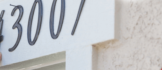 Person installing house number 43007 on an exterior wall