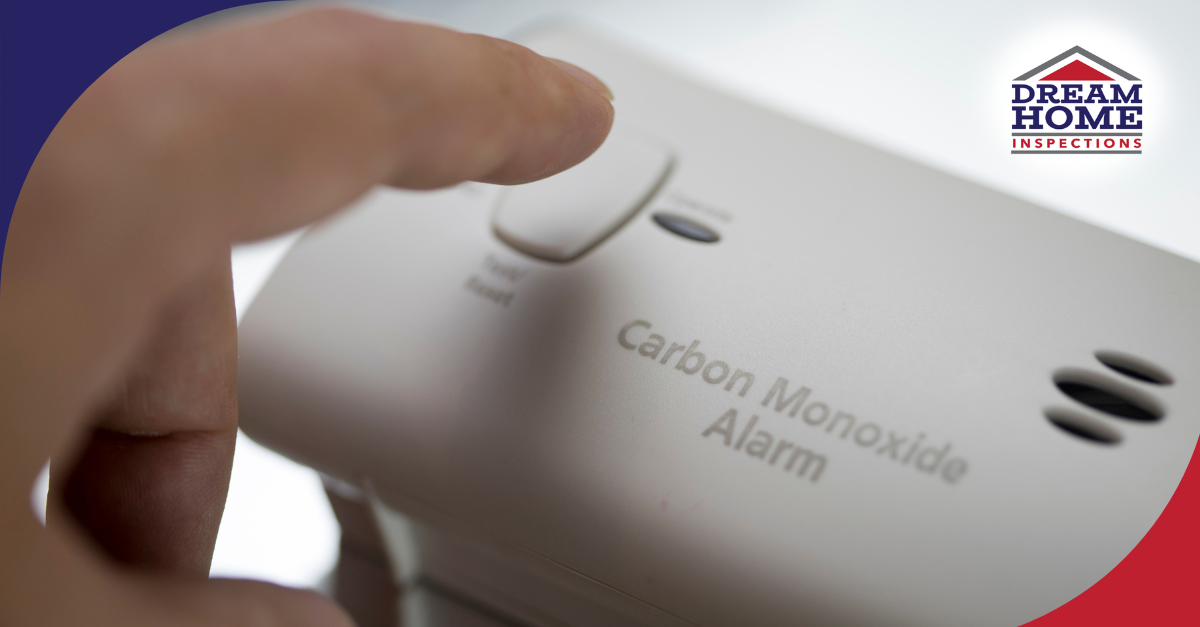 Hand pressing the test/reset button on a carbon monoxide alarm.